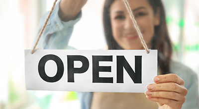 Business owner standing behind open sign