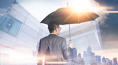 Man under an umbrella looking out at buildings