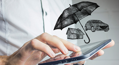 A person using a digital tablet with an umbrella, car and house illustrations above it